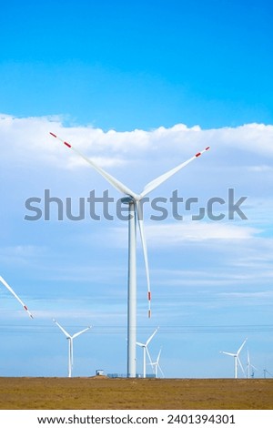 Fleet of power generators in motion. The blades of the wind farm rotate against the sky. The concept of extracting electricity from renewable sources. Wind turbine to generate electricity. Royalty-Free Stock Photo #2401394301