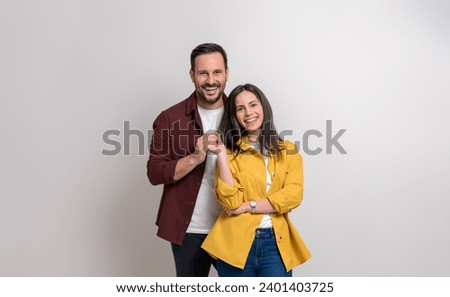 Portrait of romantic young couple smiling and holding hands while standing against white background