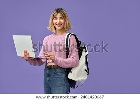 Happy pretty gen z blonde smiling girl student with short blond hair holding backpack using laptop computer wearing pink sweater looking at camera standing isolated on purple background.