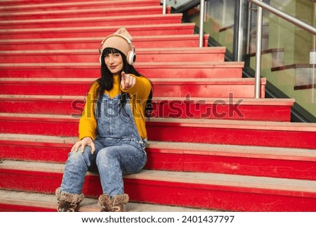 portrait woman pointing at camera sitting on colorful stairs - advertising photography