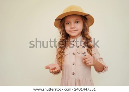 Child explorer and discoverer. Entomology. Entomologist. A child with a magnifying glass studies insects. A little girl holds a large artificial fly.  Royalty-Free Stock Photo #2401447551