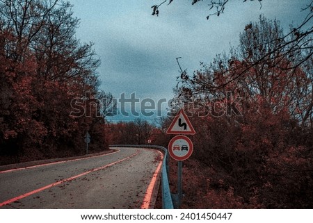 Autumn time, mountain road, orange leaves, traffic signs, dangerous turns to the left sign, no overtaking sign, slightly grainy photo, leafy road,
