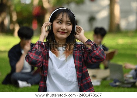 Focuses on Asian teenage school girls taking breaks to listen to music to relax from reading a textbook.