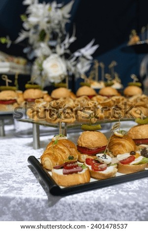 Croissants, burgers and various snacks on stands on the buffet table.