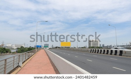 Elevated bridge over the river Car travel route There are divided routes for bicycles. A large billboard can be seen in the distance. The sky is clear and cloudy. Can be used as an illustration or bac
