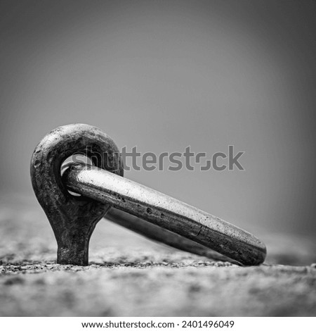 Metal ring to tie boats or cars or horses nailed to the stone with a black and white hook bw Royalty-Free Stock Photo #2401496049