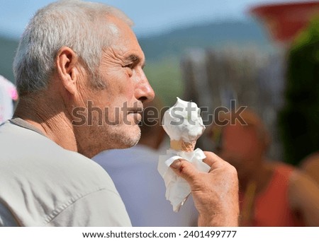 Close-up of an elderly man's mouth licking a sweet ice cream with his tongue
