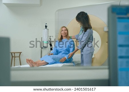Experienced radiologic technologist is preparing patient for computed tomography Royalty-Free Stock Photo #2401501617
