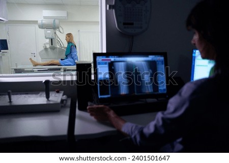 Experienced radiographer is performing digital lower limb radiography on patient Royalty-Free Stock Photo #2401501647