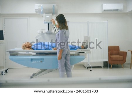 Radiologic technologist is preparing female for radiography in clinic Royalty-Free Stock Photo #2401501703