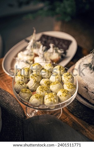 Pistachio ball cookies covered with white chocolate on dessert table