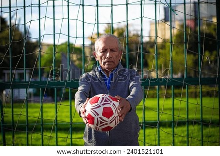 retired older man being a goalkeeper on a soccer field in a park