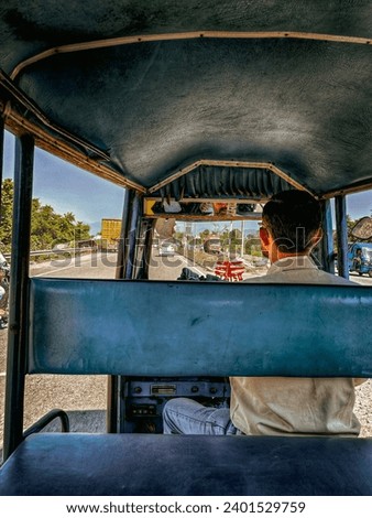 A picture capturing an auto driver amidst the vibrant streets tells a compelling story of urban life. The auto driver, a stalwart of the city's bustling streets, sits poised at the helm of the street Royalty-Free Stock Photo #2401529759