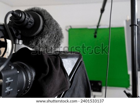 Setup in a TV studio with green screen, lights, and camera