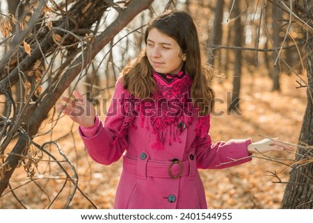 Beautiful happy smiling girl with long hair wearing pink jacket posing in autumn park. Outdoor portrait day light. Autumn mood concept. Generation Z and gen z youth. Copy empty space for text.