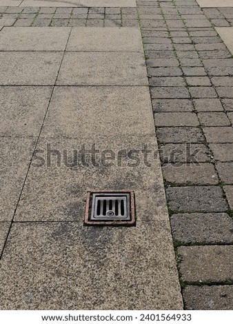 grubby paving and drain cover street Royalty-Free Stock Photo #2401564933