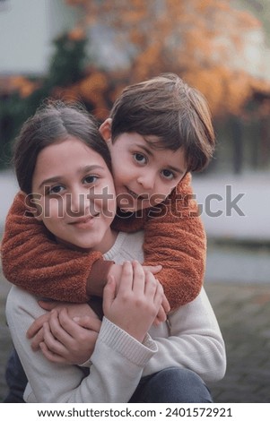 Sibling enjoying the day. Brother and sister hugging at the park while looking at the camera. Royalty-Free Stock Photo #2401572921