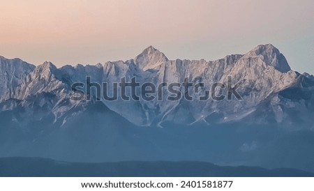 Panoramic sunrise view from summit Dobratsch on Julian Alps and Karawanks in Austria, Europe. Silhouette of endless mountain ranges with orange and pink colors of sky. Jagged sharp peaks and valleys Royalty-Free Stock Photo #2401581877