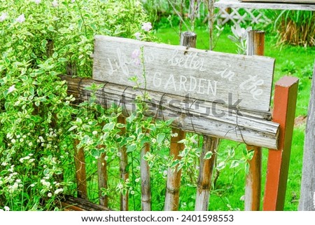 Flower garden sign with wooden home in nature,Wild daisy flowers blooming in meadow.