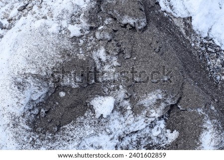 gray white texture of ash with sand and white snow in the street