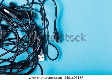 Tangled Black Cables for Modern Gadgets on Blue Background, Copy Space