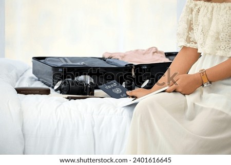Travel-Ready Woman with Luggage, Passport, and Camera on Bed, Planning Her Next Adventure While Browsing on a Tablet