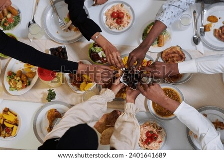 Top view of diverse hands of a Muslim family delicately grasp fresh dates, symbolizing the breaking of the fast during the holy month of Ramadan, capturing a moment of cultural unity, shared tradition Royalty-Free Stock Photo #2401641689