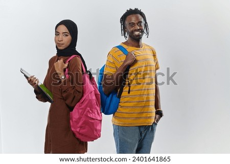Against a clean white background, two students, an African American young man and a hijab-wearing woman, collaboratively use laptops in a display of technological empowerment and inclusive education
