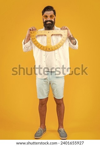 photo of smiling man with geometry protractor. man with geometry protractor isolated on yellow