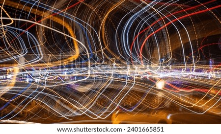 dynamic and vibrant scene of light trails, likely resulting from a long exposure photograph of city lights or traffic at night. The swirling patterns of lights in various colors, including blue, red, 