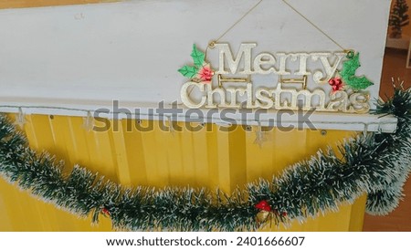 Christmas decoration of sign writing Merry Christmas red glitter material in joined up text script with fresh natural green ivy in hanging