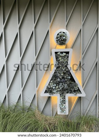 Female symbol in a frame decorated with flowers on the wall It indicates that it is a women's restroom.