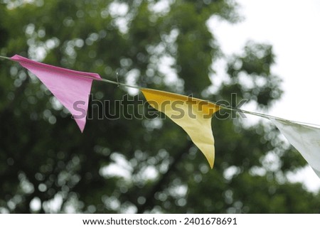 Exterior photo view of a colorful color garlands made from triangle flags pennants for a decorative decoration decor for a fun fair amusement birthday anniversary event in a park court yard garden