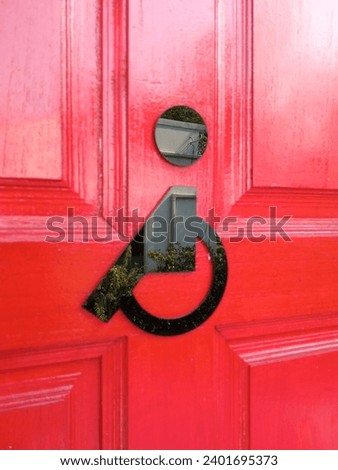 black sign for disable person toilet on the red wooden door