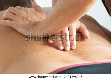 2 hands of a physiotherapist on the back of a male patient during massage therapy Royalty-Free Stock Photo #2401696345