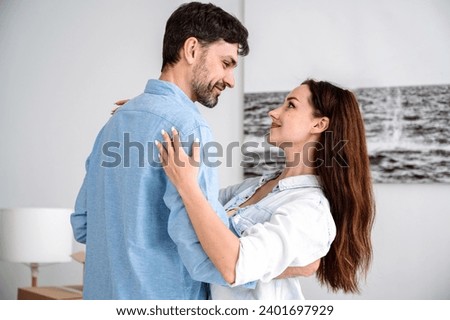 Young loving couple embracing, dancing in living room and looking in eyes each other. Husband and wife hugging, express tender, devotion and love, enjoy spending time together. Romantic relationship Royalty-Free Stock Photo #2401697929
