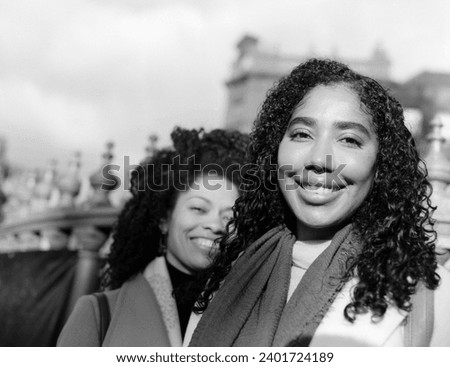 Two smiling female friends looking at camera in monochromatic analog portrait. The image is made with an old medium format analog film camera.