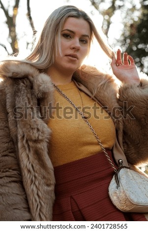 Nostalgic portrait of female model in a winter forest. She is posing in a vintage and romantic mood. She is looking straight to camera and she is wearing a fake fur coat.