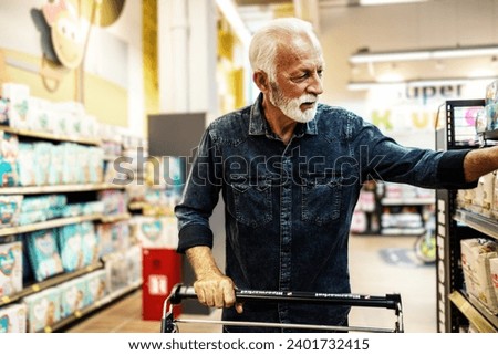 A gray-haired pensioner in a grocery store chooses groceries. Senior customer buying in supermarket.