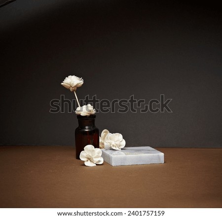 A diffuser with a brown paper background with a marble square podium and white flowers.An empty platform for display cosmetic products, food and props