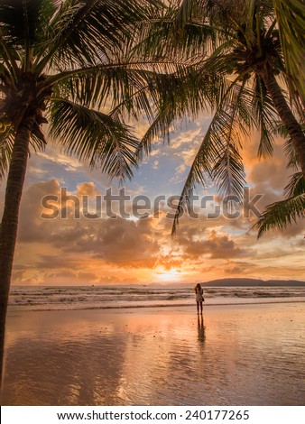 Woman taking pictures of the sunset on the beach of Ao Nang in Krabi Thailand