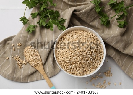Dry pearl barley in bowl, wooden spoon and parsley on table, top view Royalty-Free Stock Photo #2401783167