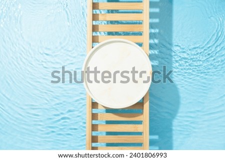 Cosmetic product presentation flat lay scene made with empty circle podium on bath tray above the blue water. Template for self-care product placement.