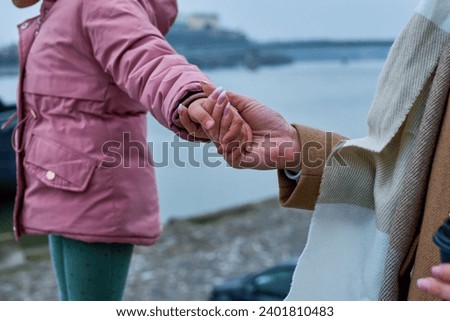 Mother's hands tenderly holding her daughter's hand, a timeless capture of the warmth and connection between them.                               