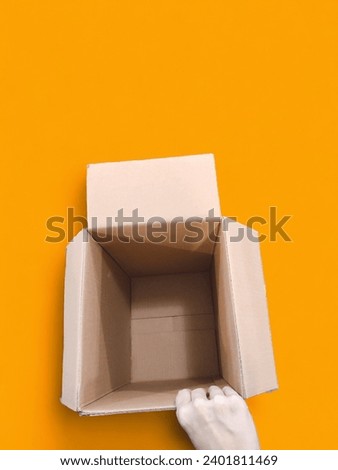 A hand holding an empty box with an orange background 