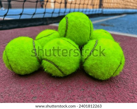 selective focus, six paddle tennis balls and the net of a blue paddle tennis court Royalty-Free Stock Photo #2401812263