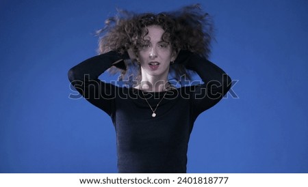 Woman playing with her hair shaking while standing on blue background