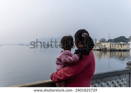 young mother with her son looking at mountain lake city landscape at morning image is taken at Jagdish Temple udaipur rajasthan india.