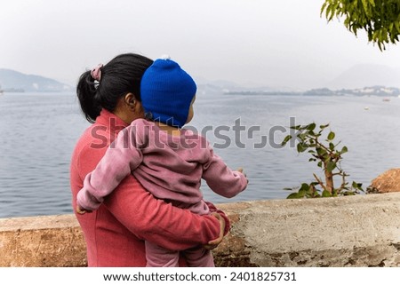 young mother with her son looking at mountain lake landscape at morning image is taken at Jagdish Temple udaipur rajasthan india.
