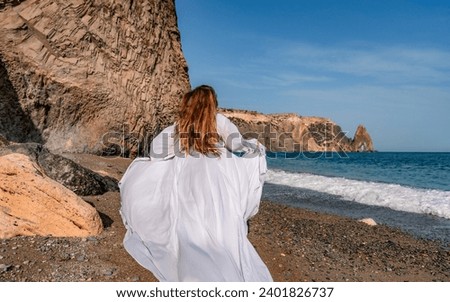 Woman beach white dress flying on Wind. Summer Vacation. A happy woman takes vacation photos to send to friends.
